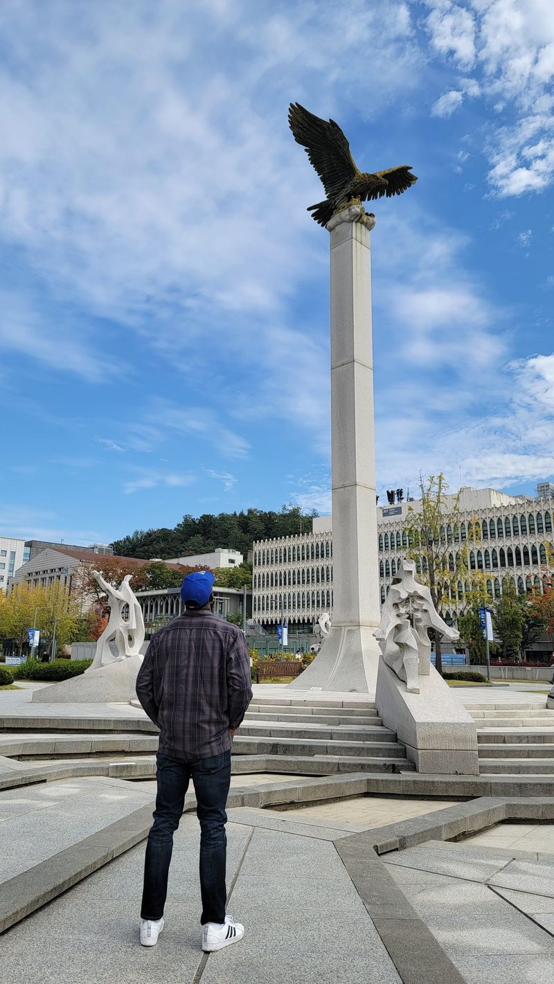 Ade from behind, looking up at the eagle statue on the Yonsei campus